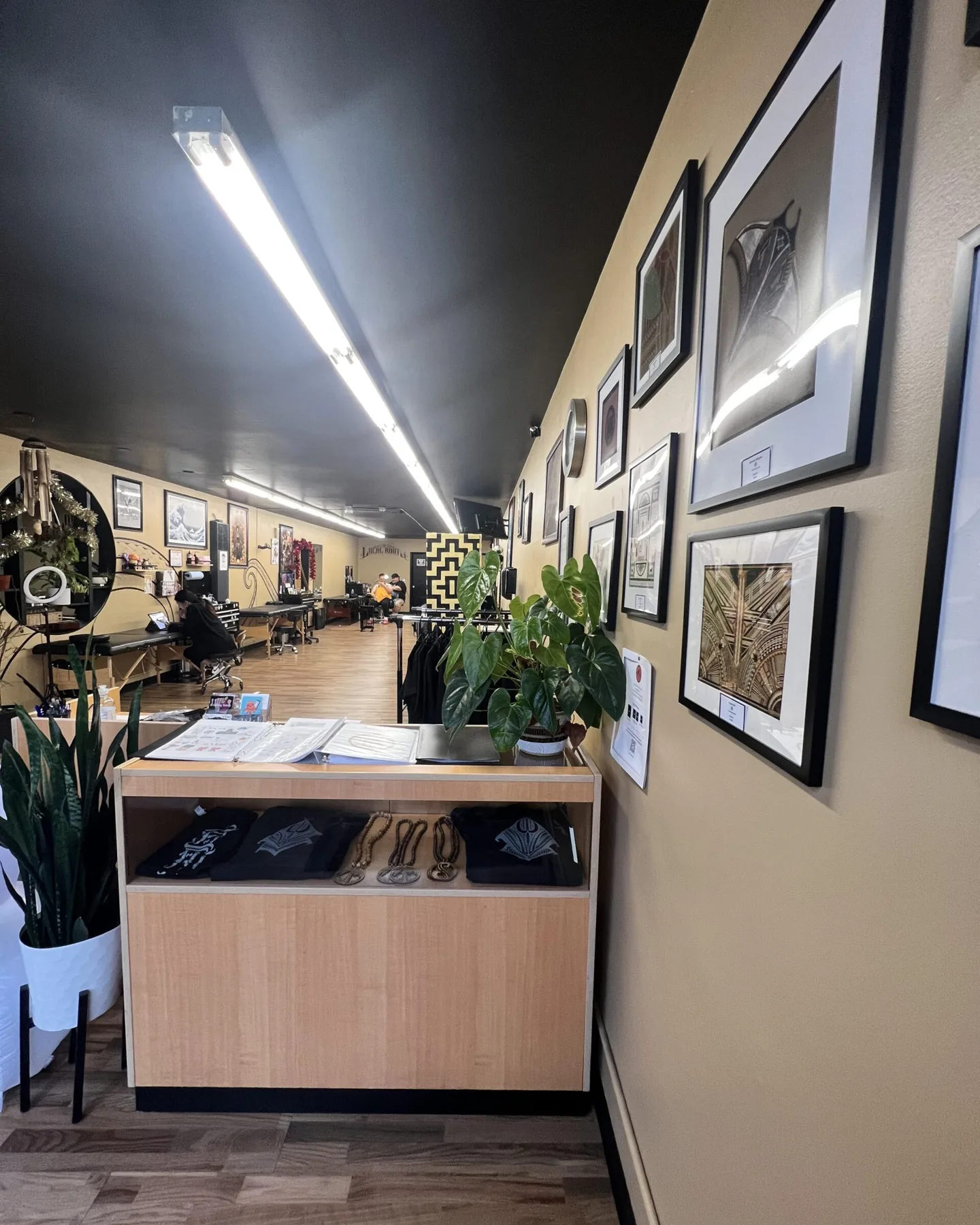 The front desk at Local Roots Ink, with the framed art wall behind it